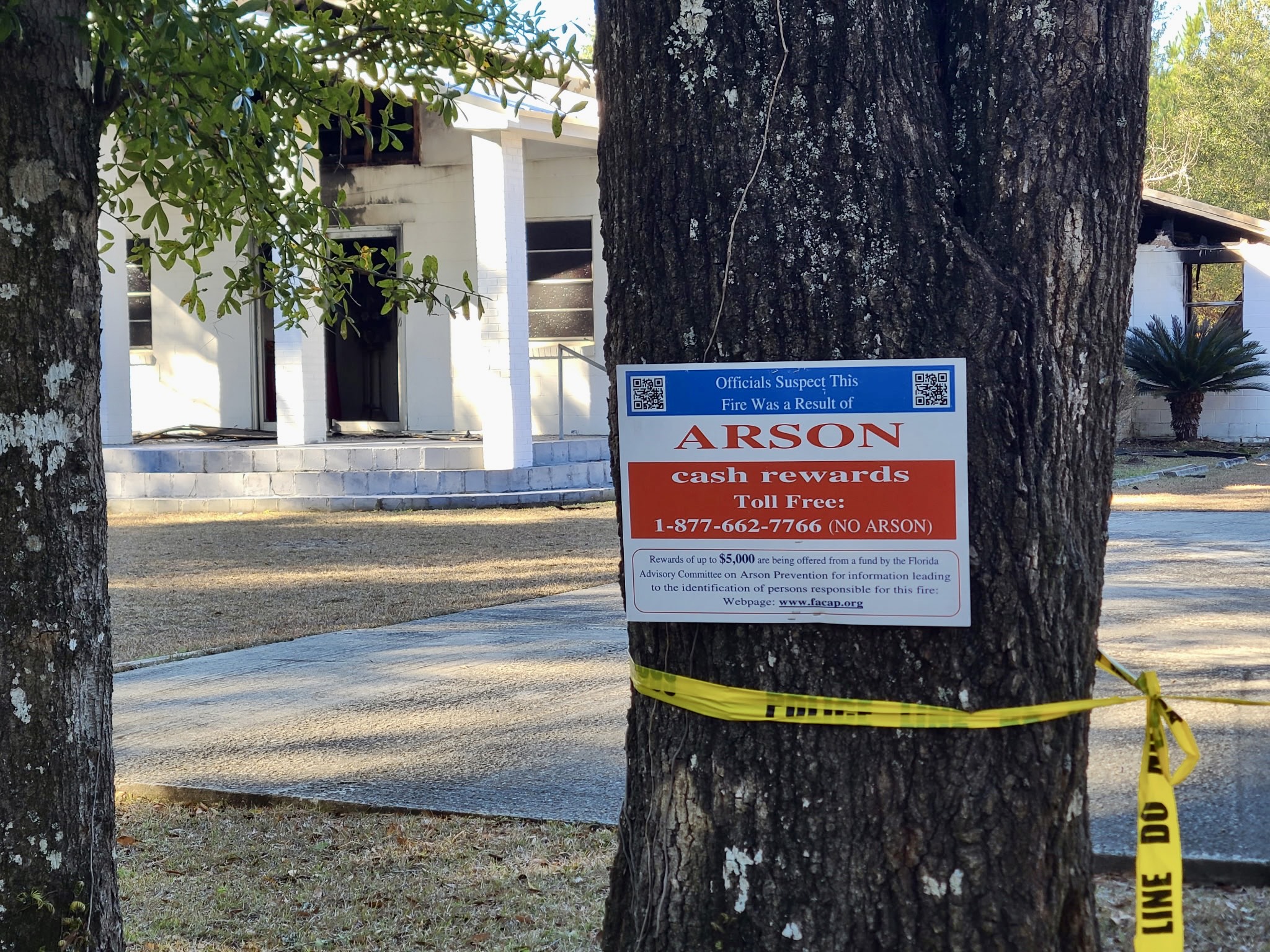 Another exterior angle of the same fire-damaged church, emphasizing the length of the building and burn marks along the roof line.